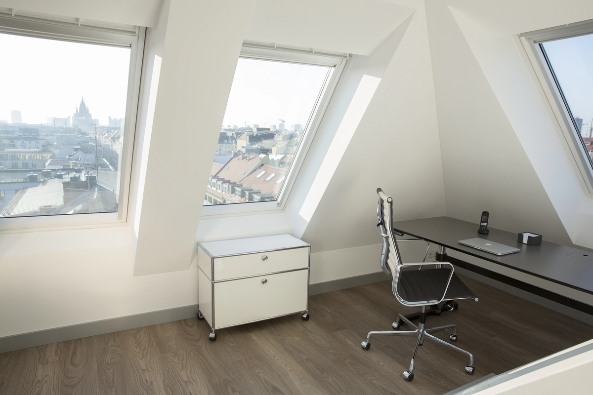 Workstation with desk and chair under sloping ceiling.