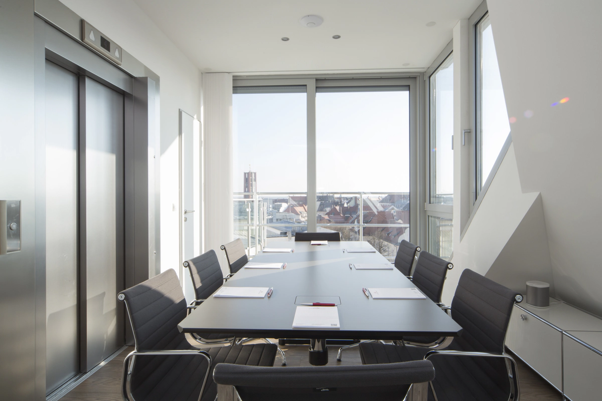 Konferenzraum mit großem Tisch und Fensterblick.